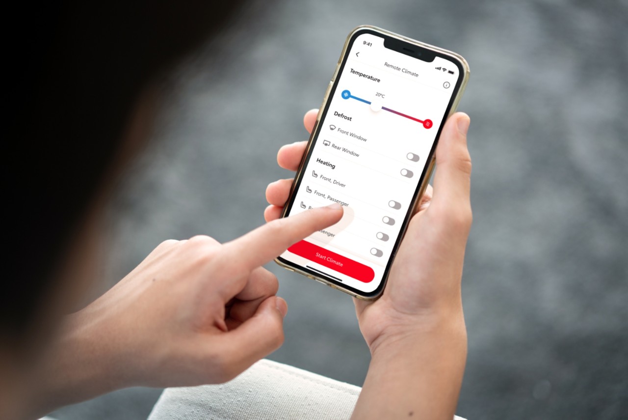 Osoba drži pametni telefon na kojem se prikazuje aplikacija MyToyota. Njihova lijeva ruka dodiruje zaslon da bi daljinski postavila klima uređaj u svojem automobilu.